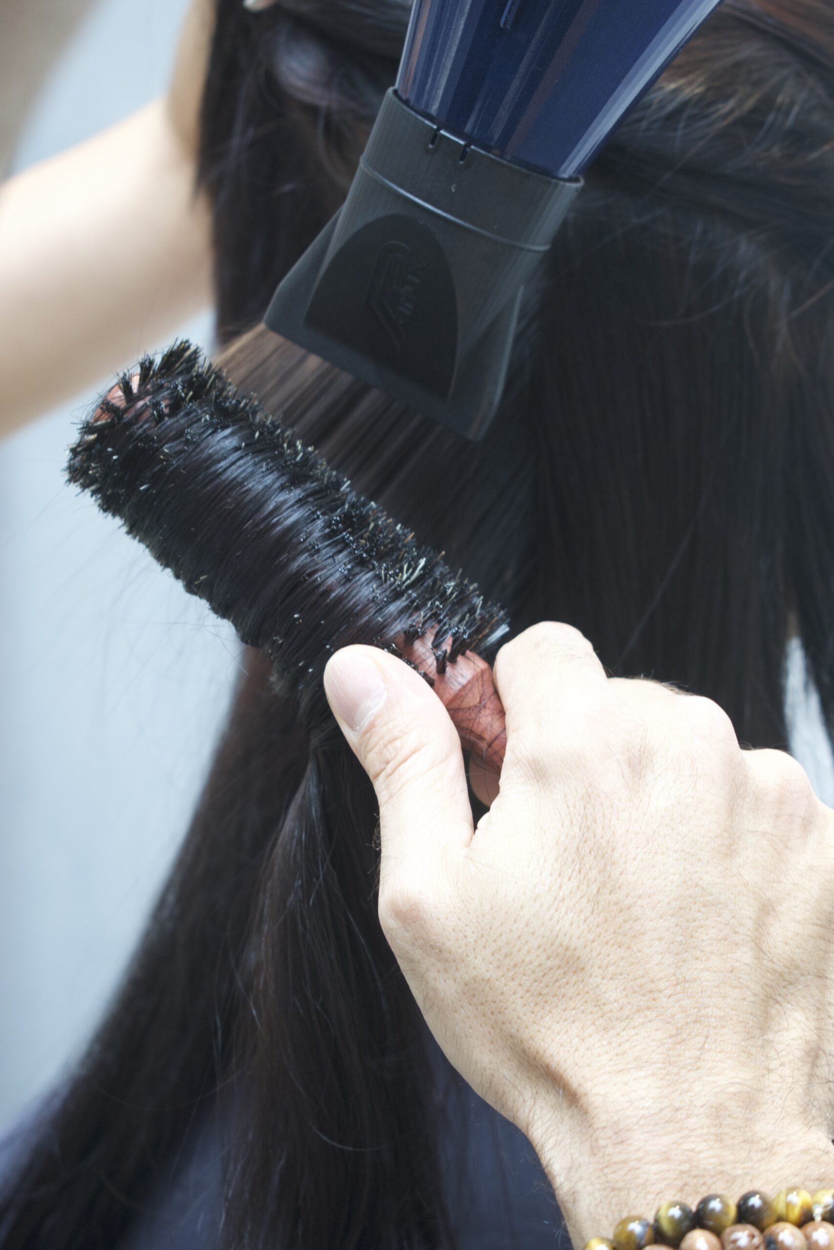Close-up of brush and blow dryer nozzle working together to smooth and style hair.