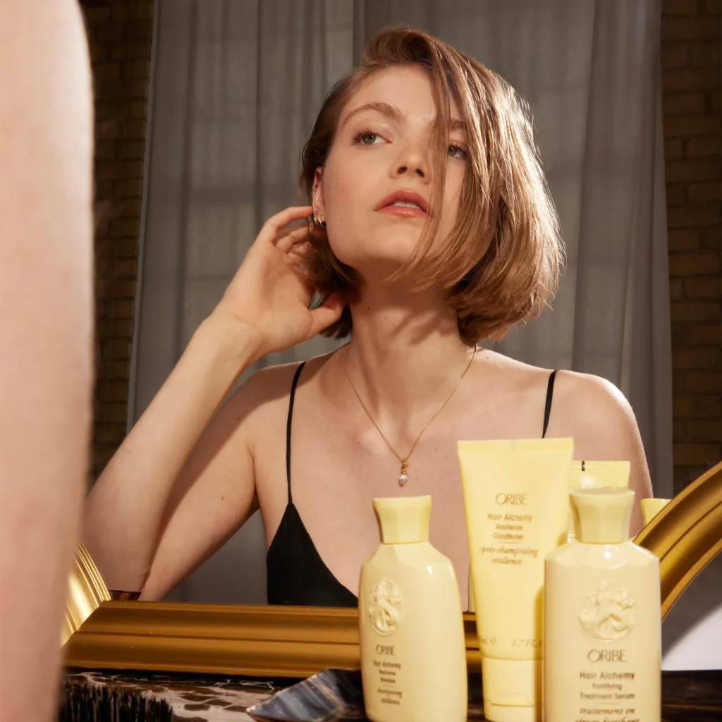 model with healthy hair posing alongside the oribe alchemy collection